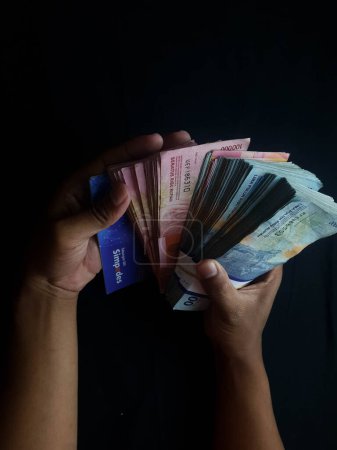 Foto de Persona con millones de rupias sobre un fondo negro - Imagen libre de derechos