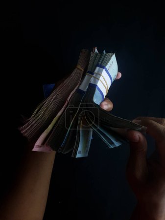 Foto de Persona con millones de rupias sobre un fondo negro - Imagen libre de derechos