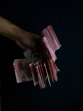 Foto de Mano con millones de rupias sobre un fondo negro - Imagen libre de derechos