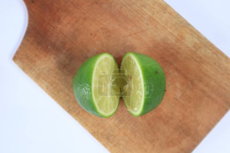 Foto de Lima verde fresca sobre tabla de madera sobre fondo blanco - Imagen libre de derechos