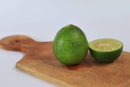 Foto de Lima verde fresca sobre tabla de madera sobre fondo blanco - Imagen libre de derechos