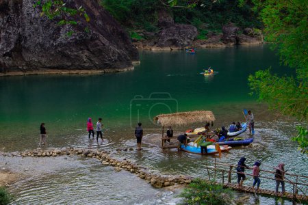 Foto de Yogyakarta, Indonesia - 3 de agosto de 2023: Vista del río donde el agua es muy clara y verde. Gente paseando en canoa en Kedung Jati Parang, Selopamioro. - Imagen libre de derechos