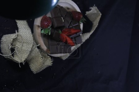 Photo for Chocolate bars with strawberries on a black background - Royalty Free Image