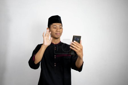 Téléchargez les photos : Jeune asiatique musulman homme tenant smartphone - en image libre de droit