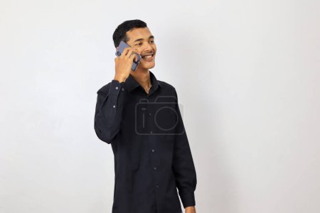 Foto de Hombre joven asiático en camisa azul marino usando teléfono inteligente sobre fondo blanco - Imagen libre de derechos