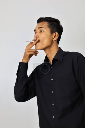 Photo for Asian man in black shirt smoking cigarette - Royalty Free Image