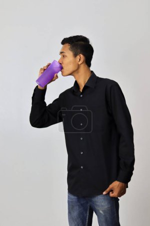 Foto de Hombre asiático con botella de agua sobre fondo gris estudio. - Imagen libre de derechos