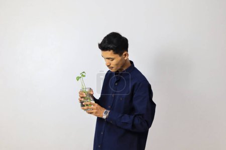 Téléchargez les photos : Homme tenant une plante d'intérieur sur un fond blanc - en image libre de droit