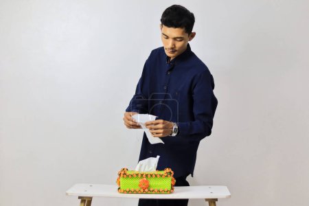 Téléchargez les photos : Asiatique jeune homme prenant papier tissu de la boîte - en image libre de droit
