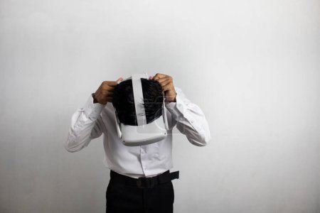 Foto de Hombre joven con camisa blanca ordenada usando auriculares de realidad virtual. Aislado sobre retrato de estudio de fondo blanco. VR, futuro, gadgets, tecnología, educación en línea, aprendizaje, concepto de videojuegos - Imagen libre de derechos