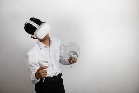 Téléchargez les photos : Jeune homme en chemise blanche soignée utilisant casque de réalité virtuelle. Isolé sur fond blanc portrait studio. VR, futur, gadgets, technologie, éducation en ligne, apprentissage, concept de jeu vidéo - en image libre de droit