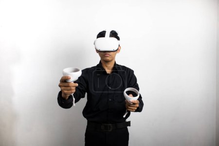 Téléchargez les photos : Jeune homme en chemise noire soignée utilisant casque de réalité virtuelle. Isolé sur fond blanc portrait studio. VR, futur, gadgets, technologie, éducation en ligne, apprentissage, concept de jeu vidéo - en image libre de droit