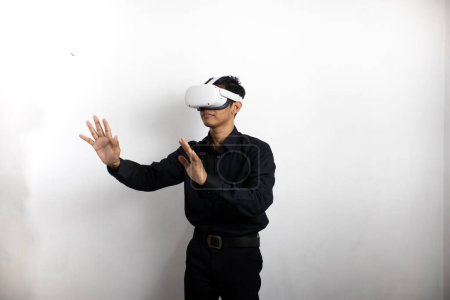 Téléchargez les photos : Jeune homme en chemise noire soignée utilisant casque de réalité virtuelle. Isolé sur fond blanc portrait studio. VR, futur, gadgets, technologie, éducation en ligne, apprentissage, concept de jeu vidéo - en image libre de droit