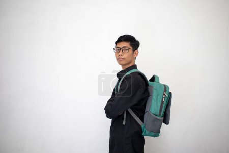 Photo for Asian man in neat black clothes is carrying a green backpack on a white background. a student carrying a bag with confidence. - Royalty Free Image