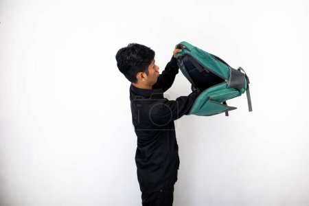 Foto de Asiático hombre en limpio negro ropa es mirando el contenido de su bolsa - Imagen libre de derechos
