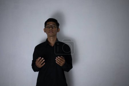 Téléchargez les photos : Asiatique homme en pur noir vêtements prie sur fond de studio - en image libre de droit