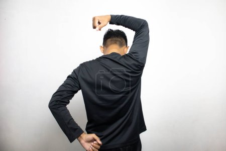 Téléchargez les photos : Vue arrière de l'homme asiatique en vêtements noirs debout sur fond de studio blanc - en image libre de droit
