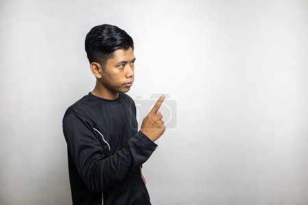 Téléchargez les photos : Émotionnel asiatique l'homme dans noir vêtements posant sur blanc studio fond - en image libre de droit