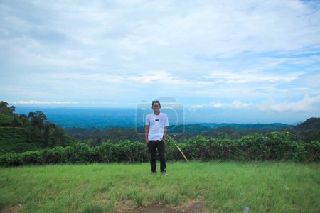 Téléchargez les photos : Asiatique homme avec debout à prairie verte, ciel nuageux fond - en image libre de droit