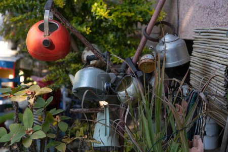 Rusty Teapots Repurposed: Sustainable Garden Decor for a Greener Tomorrow on a Sunny Day, Embodying Reuse and Rustic Charm.