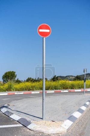 No-entry traffic sign stands prominently against the springtime landscape of Israel, symbolizing road restrictions with natural beauty behind.