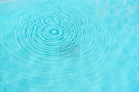 Vue de dessus de l'eau claire de la piscine bleue avec des ondulations, créant une atmosphère sereine et tranquille.