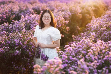 Foto de Retrato de mujer joven asiática viajero feliz con vestido blanco disfrutando en flor blanca o púrpura Michaelmas Daisy campo de flores en el jardín natural de en Chiang Mai, Tailandia, viaje relajar vacaciones - Imagen libre de derechos