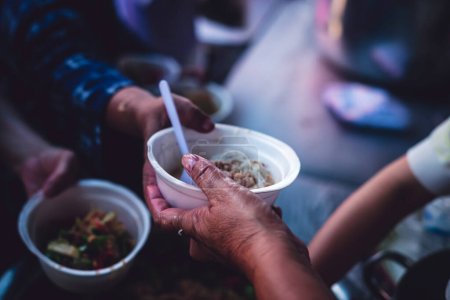 Foto de Asistencia humanitaria de voluntarios que comparten alimentos para los hambrientos y pobres: conceptos de cuidado y donación. - Imagen libre de derechos