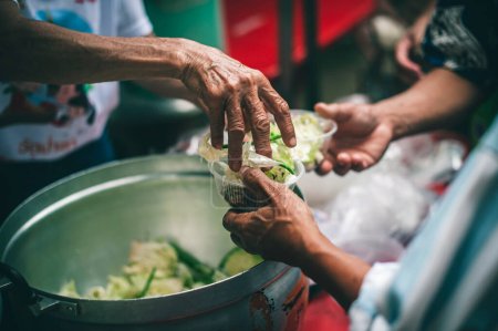 Téléchargez les photos : Fournir gratuitement de la nourriture des bénévoles aux pauvres affamés : concept de don alimentaire, partage de nourriture - en image libre de droit