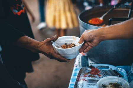 Hands of poor people asking for food from volunteers helping: concept of food donation