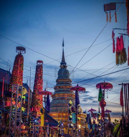 Foto de Lamphun, Tailandia - 4 de septiembre de 2022: Salak yom en Wat Phra That Hariphunchai en Lamphun. La tradición de hacer mérito, los árboles de lotería teñidos altos están decorados con papel de diferentes colores y artículos de ropa para rendir homenaje a las almas - Imagen libre de derechos
