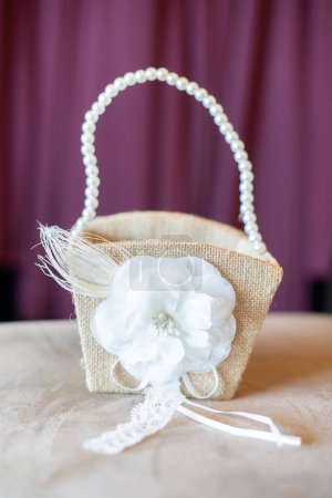 Téléchargez les photos : Panier en osier avec poignée en perle et décoration de fleurs blanches fond violet - en image libre de droit