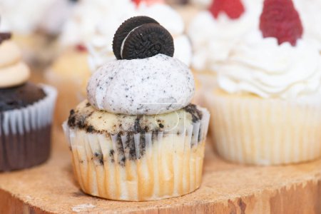 Téléchargez les photos : Cupcakes à la vanille et au chocolat avec crème fouettée et biscuits sur le dessus à la table de dessert de mariage - en image libre de droit
