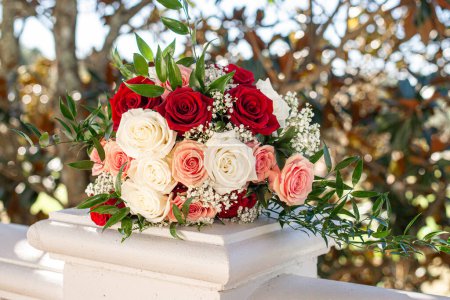 Photo for Gorgeous back lit bridal bouquet of red, pink and whit roses - Royalty Free Image