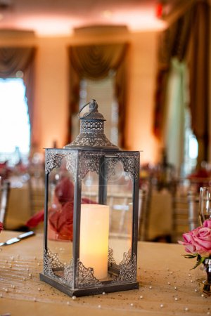 Photo for Black ornate candle lantern centerpiece on wood table at Wedding reception - Royalty Free Image