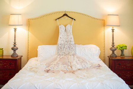 Photo for Gorgeous white lace wedding dress on hanger on bed - Royalty Free Image