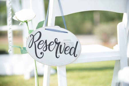 Foto de Cartel de boda blanco redondo "reservado" con texto negro colgado de la silla en la isla de la ceremonia de boda - Imagen libre de derechos