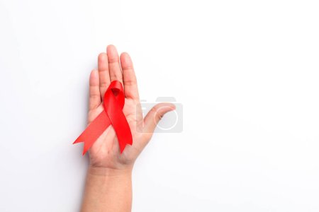 Téléchargez les photos : Photo rapprochée de la main de la femme tenant un ruban rouge sur fond blanc avec copyspace. Concept du jour du sida - en image libre de droit
