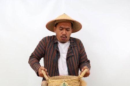 Téléchargez les photos : Fermier asiatique debout tout en tenant un panier lourd. Isolé sur fond blanc - en image libre de droit