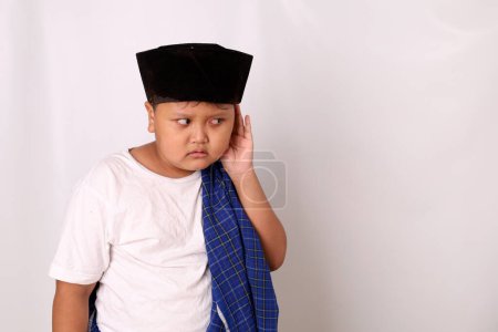 Foto de Retrato asiático chico de pie mientras escucha algo con la mano mantenga la oreja. Aislado sobre fondo blanco - Imagen libre de derechos