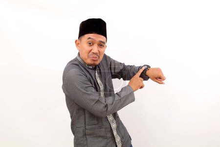 Photo for Asian muslim man standing while pointing on his watch. Isolated on white background - Royalty Free Image