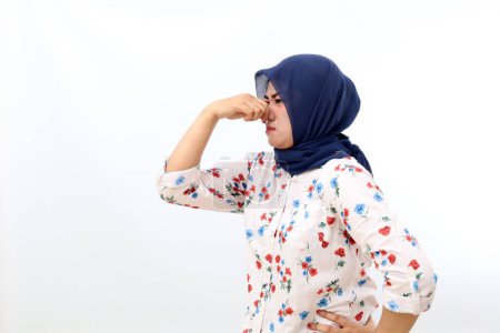Téléchargez les photos : Side view of Asian muslim woman standing while covering her nose. Bad smell concept - en image libre de droit