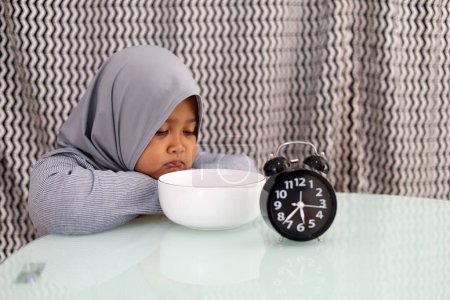 Photo for Asian muslim little girl waiting for breaking her fast. Ramadhan concept - Royalty Free Image