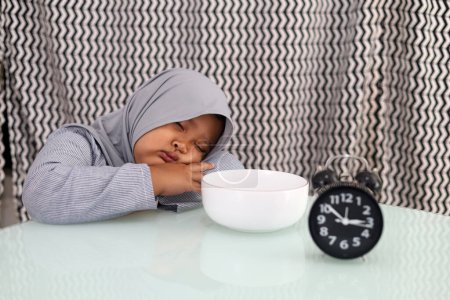 Photo for Asian muslim little girl sleeping when waiting for breaking her fast. Ramadhan concept - Royalty Free Image