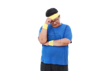 Foto de Estresado asiático hombre con sobrepeso en ropa deportiva de pie mientras sostiene la cabeza. Aislado sobre blanco - Imagen libre de derechos