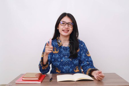 Téléchargez les photos : Asiatique femme en batik korpri, indonésien traditionnel travailleur uniforme pointant sur vous dans bureau bureau - en image libre de droit