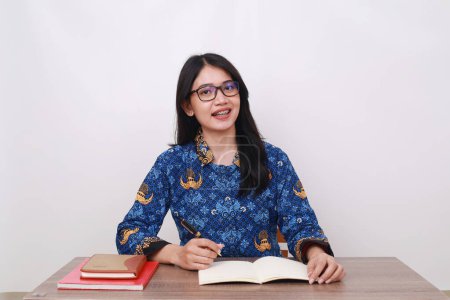 Photo for Asian female wearing batik korpri, indonesian traditional worker uniform in office desk - Royalty Free Image
