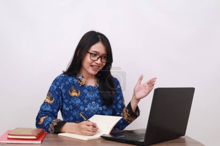 Photo for Attractive Asian female in batik korpri, indonesian traditional worker uniform working online - Royalty Free Image
