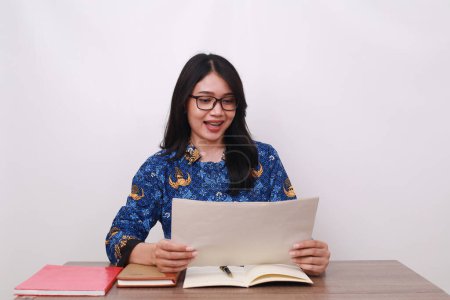 Photo for Excited Asian female in batik korpri, indonesian traditional worker uniform holding paper - Royalty Free Image