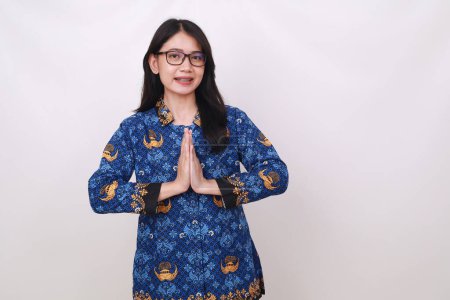 Téléchargez les photos : Amical Happy Asian femelle en batik korpri, indonésien uniforme traditionnel faire geste accueillant - en image libre de droit